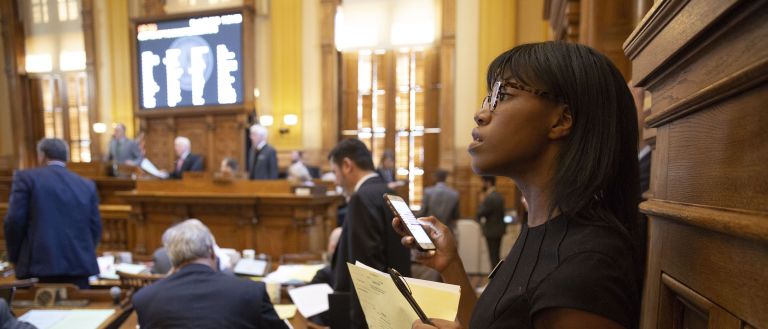 Student on senate floor <p>Janelle George, an aide to Senate Majority Leader Bill Cowsert, scans the senate floor in search of legislators needed to sign a proclamation.</p>