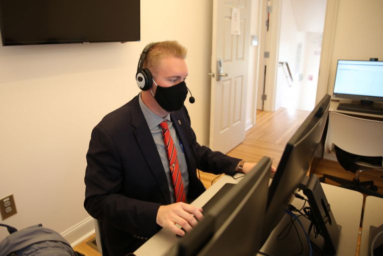 Man in suit using computer <p>FACS financial planning major Rayce Foster works with a virtual VITA client.</p>